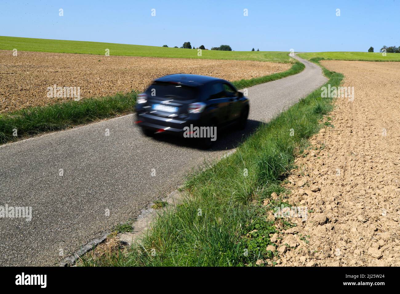 Un coche en una carretera estrecha en el campo. Foto de stock