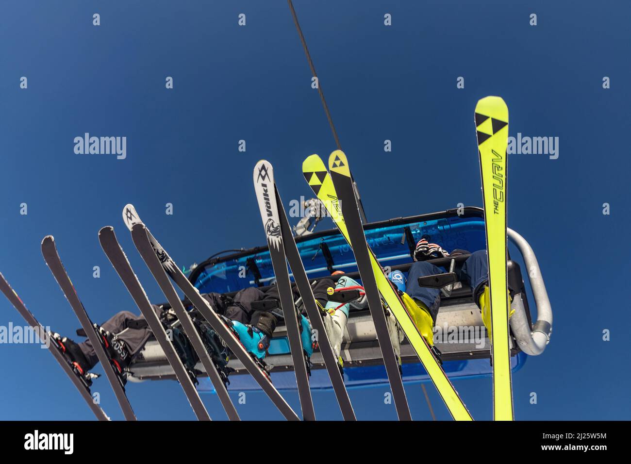 SPINDLERUV MLYN, REPÚBLICA CHECA - 10 DE MARZO. 2022: Vista de la telesilla, esquiadores y esquís en un día soleado, en el fondo el cielo azul turquesa. SPI Foto de stock