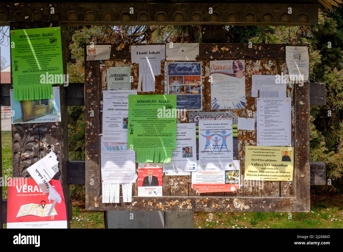 tablón de anuncios tradicional cubierto en múltiples avisos anclados en el centro de la ciudad de lenti, condado de zala, hungría Foto de stock
