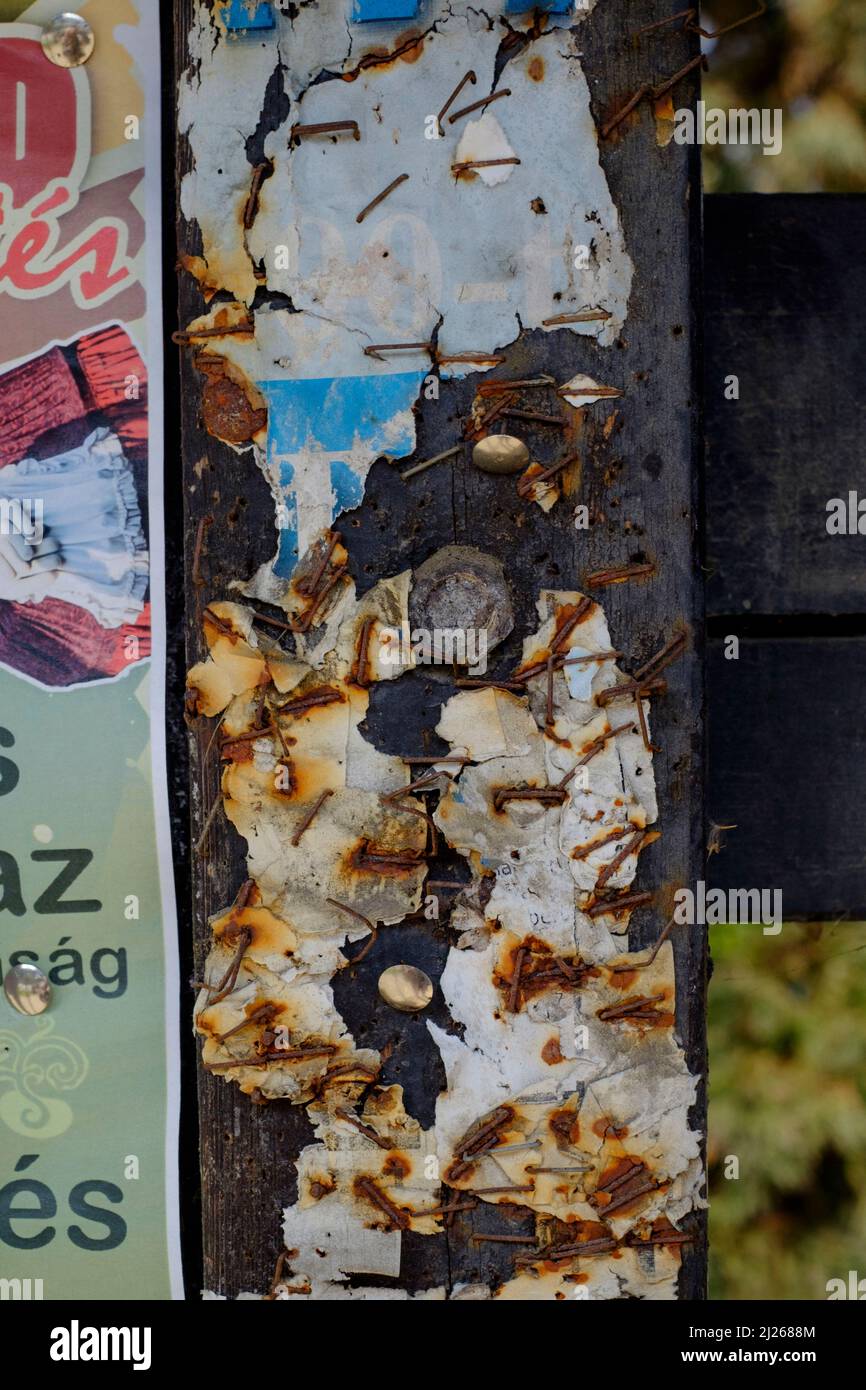 cierre el tablón de anuncios tradicional cubierto de restos de múltiples avisos anclados en el centro de la ciudad de lenti, condado de zala, hungría Foto de stock