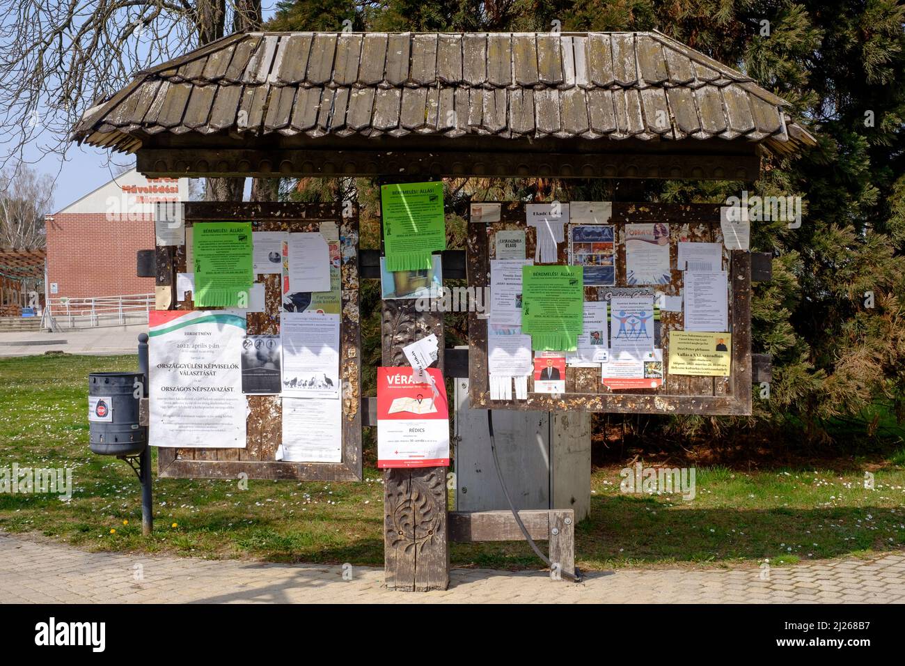 tablón de anuncios tradicional cubierto en múltiples avisos anclados en el centro de la ciudad de lenti, condado de zala, hungría Foto de stock