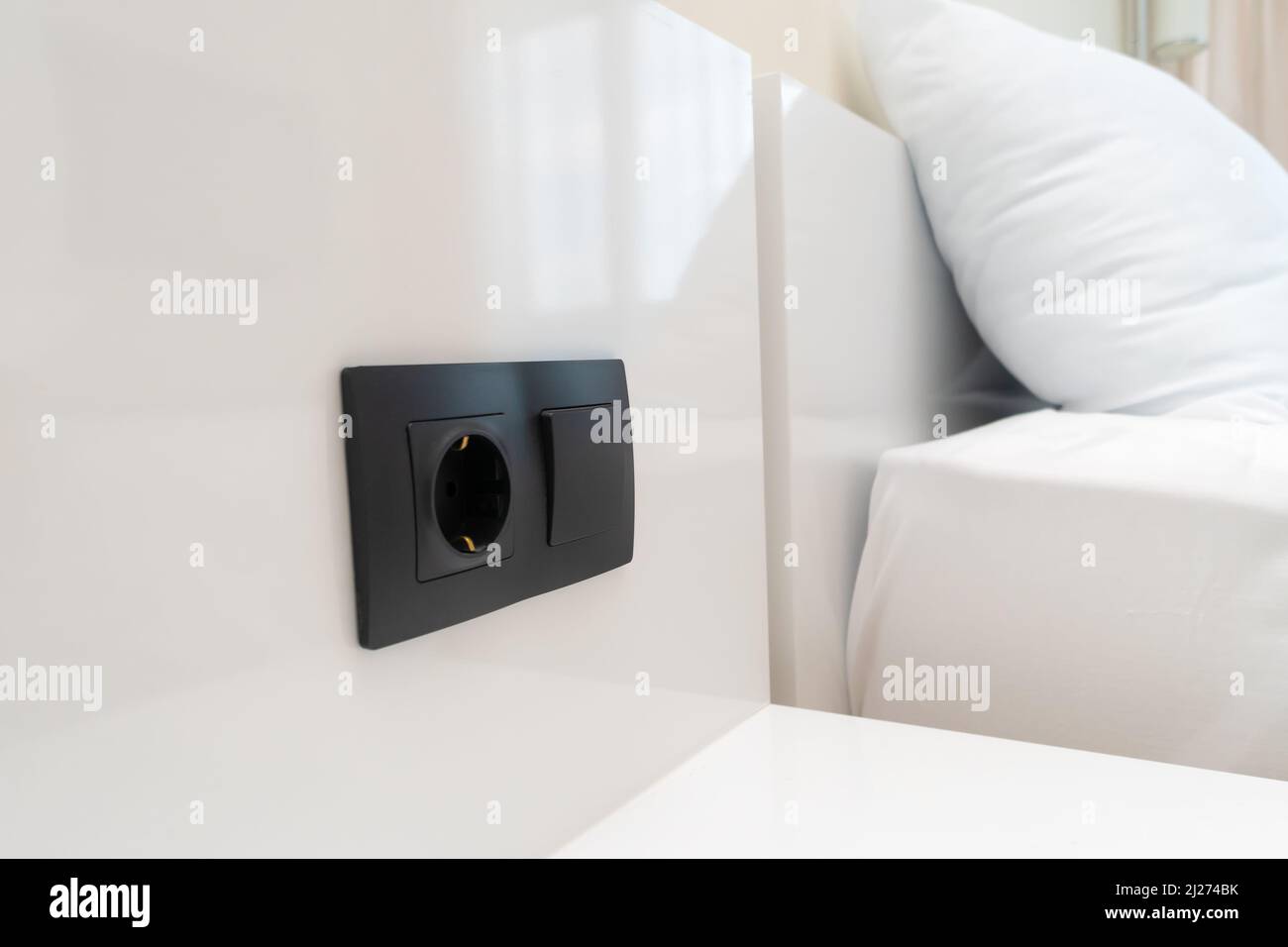 Primer plano de un interruptor negro y enchufe en una pared blanca cerca de  la cama Fotografía de stock - Alamy