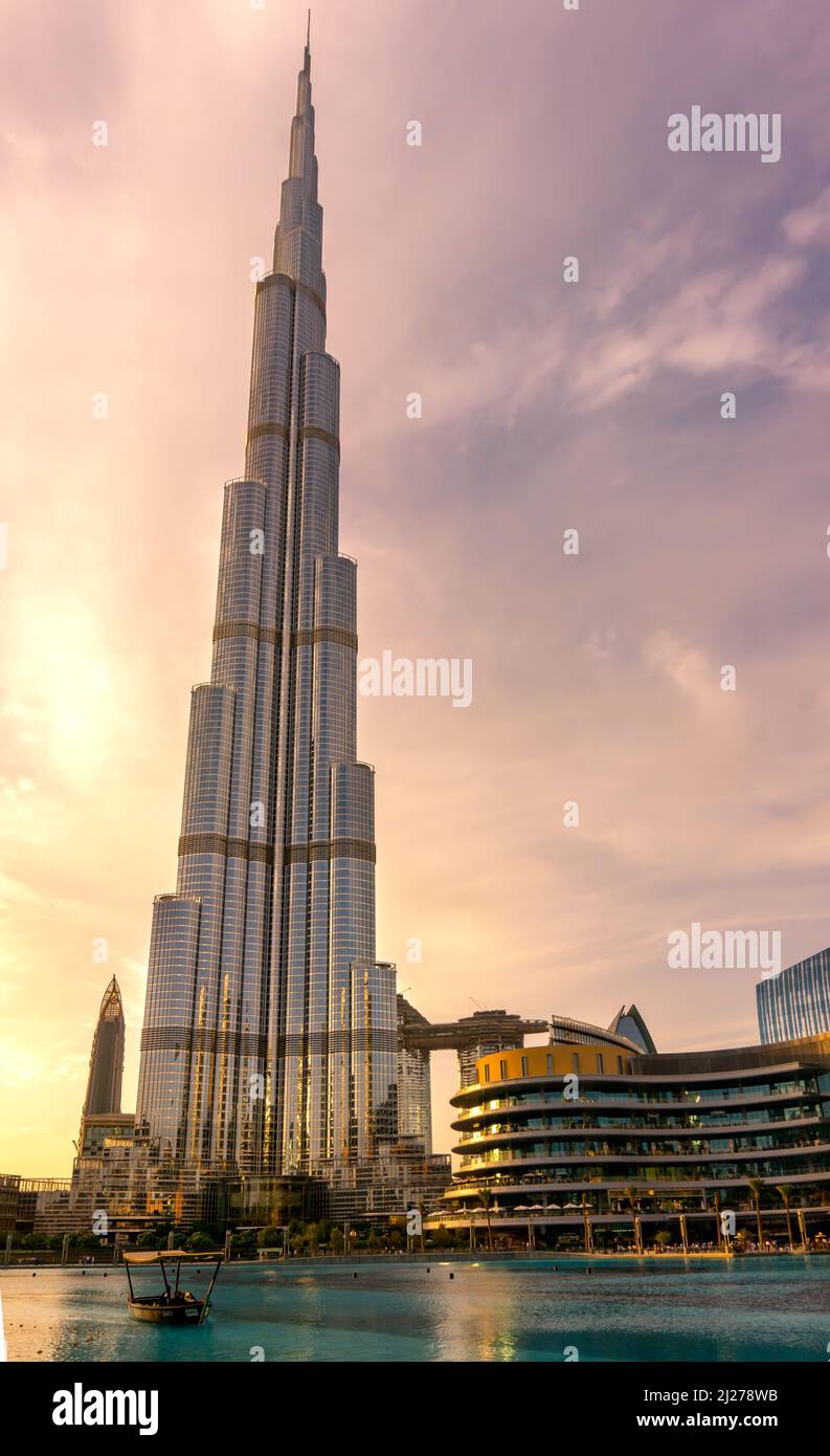 Dubai, EAU - 06.11.2018 : Burj Khalifa en la puesta de sol con un barco en el agua de la fuente Foto de stock