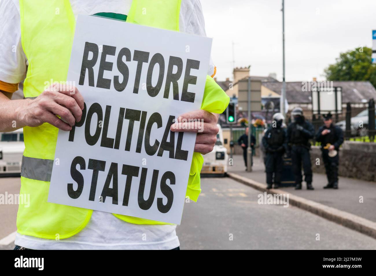 25/07/2010, Lurgan, Irlanda del Norte. Un hombre lleva a cabo un cartel de protesta que dice 'Restaurar el estatus político' mientras las familias de prisioneros republicanos en la prisión de Maghaberry tienen un desfile ilegal a través de Lurgan. Foto de stock