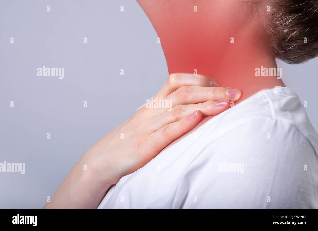 Mujer que sufre de dolor de garganta. Mano tocando el cuello con el punto rojo de cerca. Cuidado de la salud, concepto de enfermedad. Gripe, resfriado, inflamación. Fotografías de alta calidad Foto de stock