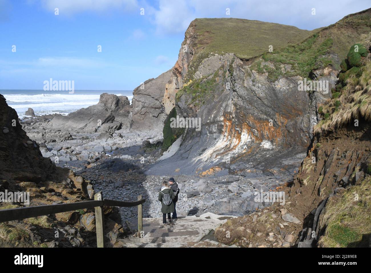 El empinado acercamiento a la bahía de Sandymouth con escarpados acantilados distorsionados que se elevan sobre la playa rocosa, en la costa atlántica de Cornwall del norte de Reino Unido Foto de stock