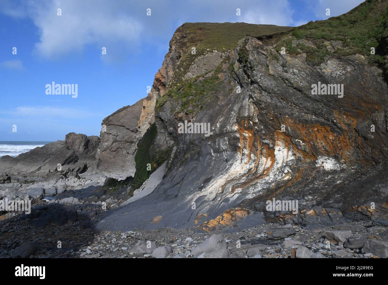 Bahía de Sandymouth con escarpados acantilados distorsionados que se elevan sobre la playa rocosa, en la costa atlántica del norte de Cornwall.UK Foto de stock
