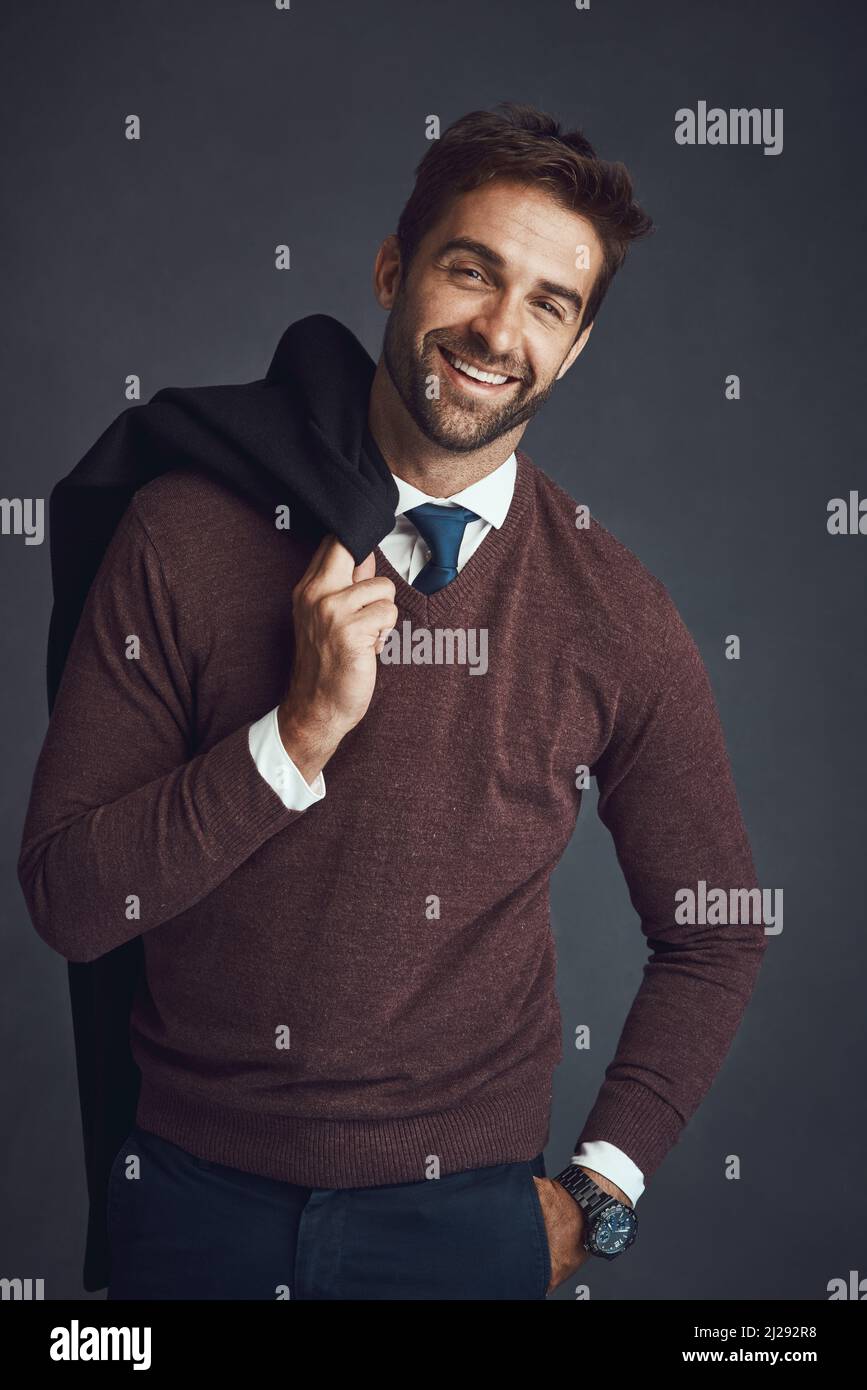 El hombre consciente del estilo. Retrato de estudio de un joven vestido con estilo que lleva su chaqueta sobre un fondo gris. Foto de stock