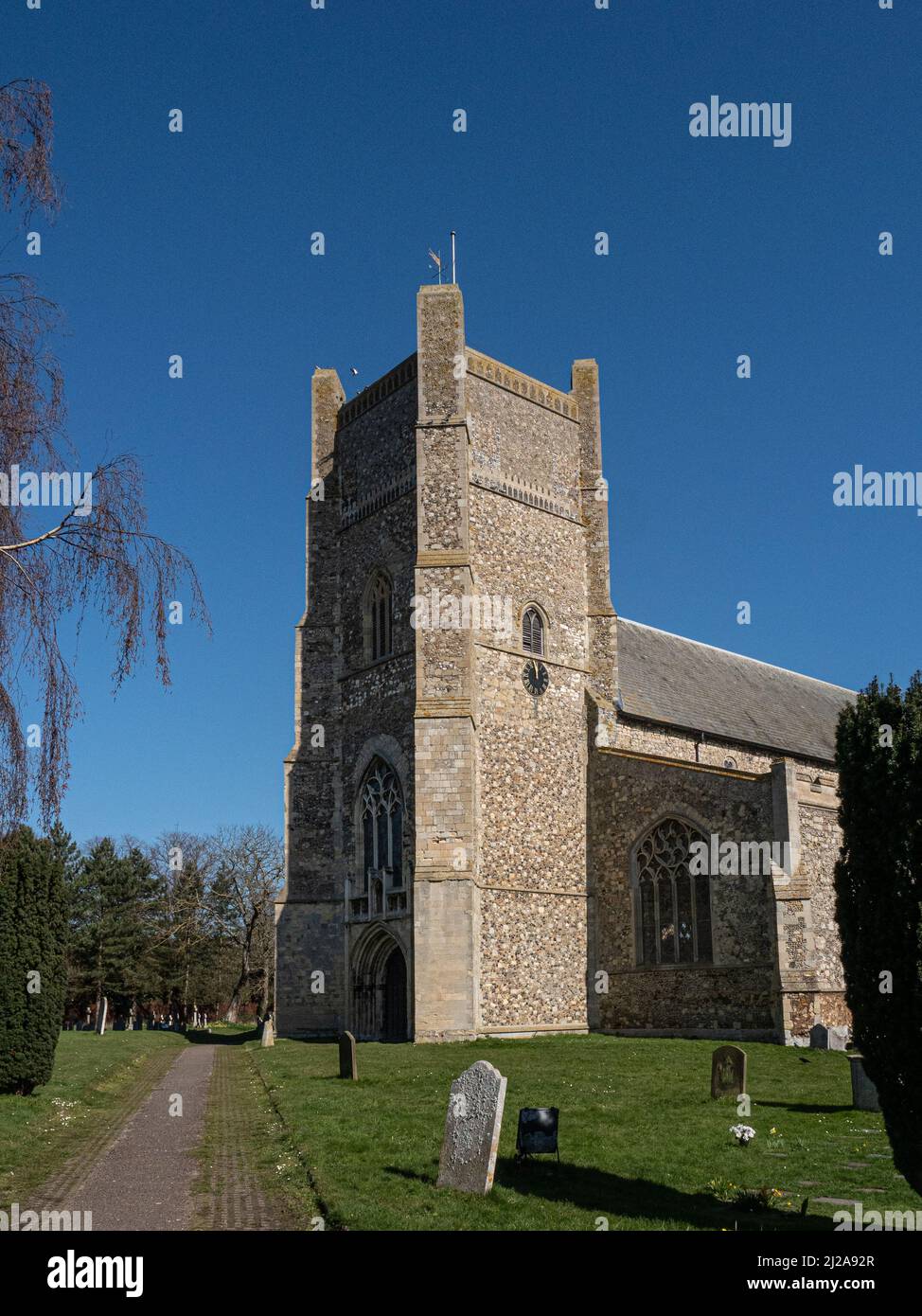 La torre de la Iglesia de San Bartolomé, Orford, se enmarca en un claro cielo azul Foto de stock