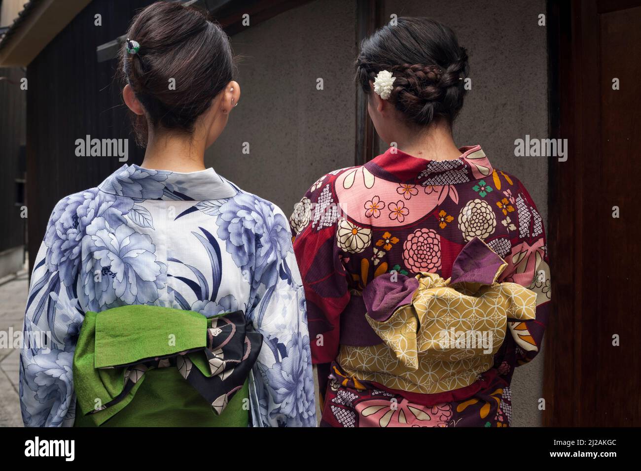 Vista horizontal de dos mujeres jóvenes, con la espalda mirando, llevando yukatas tradicionales en Gion, Distrito de Higashiyama del Sur, Kyoto, Japón Foto de stock