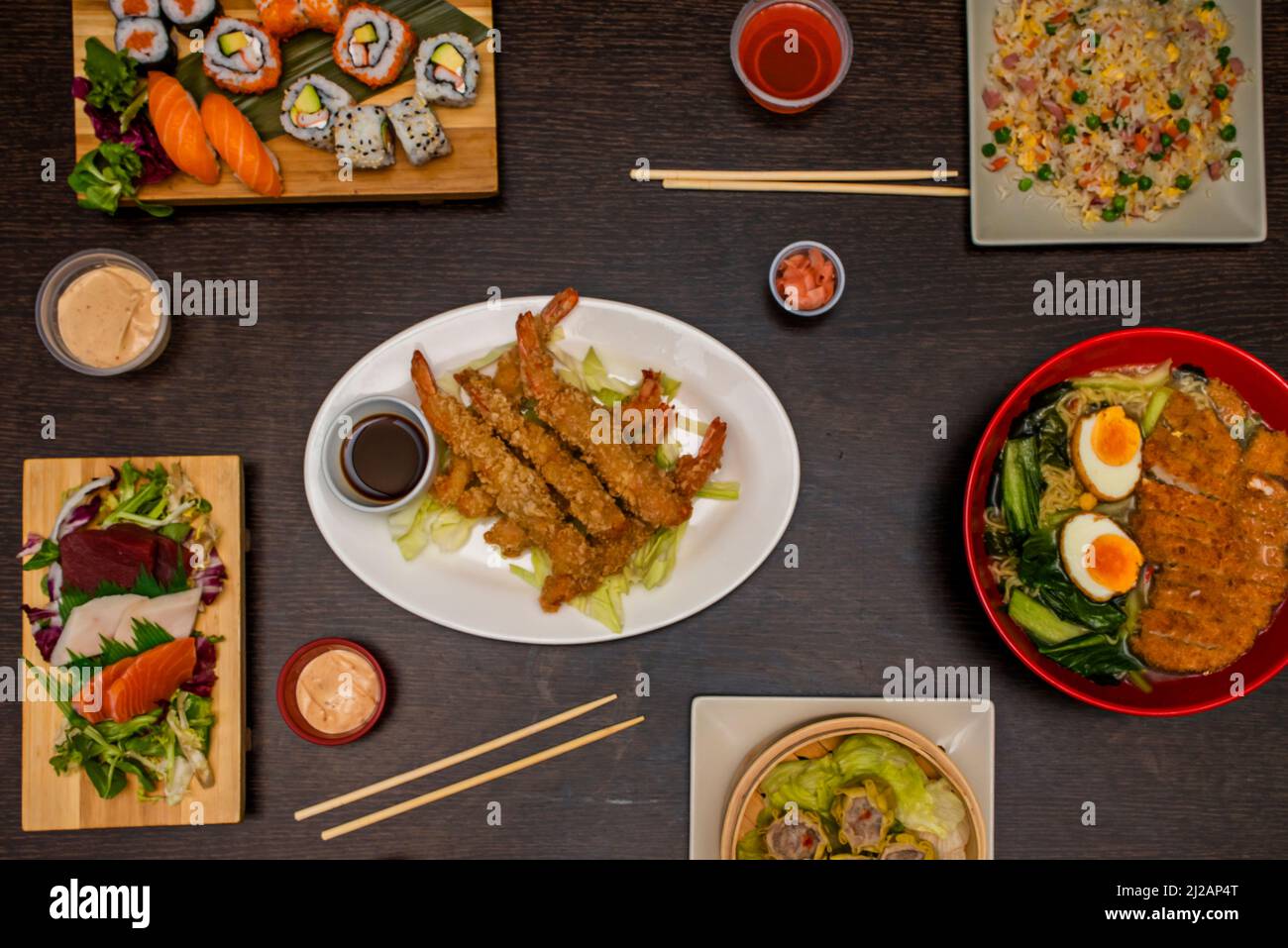conjunto de platos de comida asiática, con ramen, tres delicias de arroz,  tempura de camarones, maki de atún, uramaki aguacate surimi, algas nori,  huevas de masago, amapola y se Fotografía de stock -