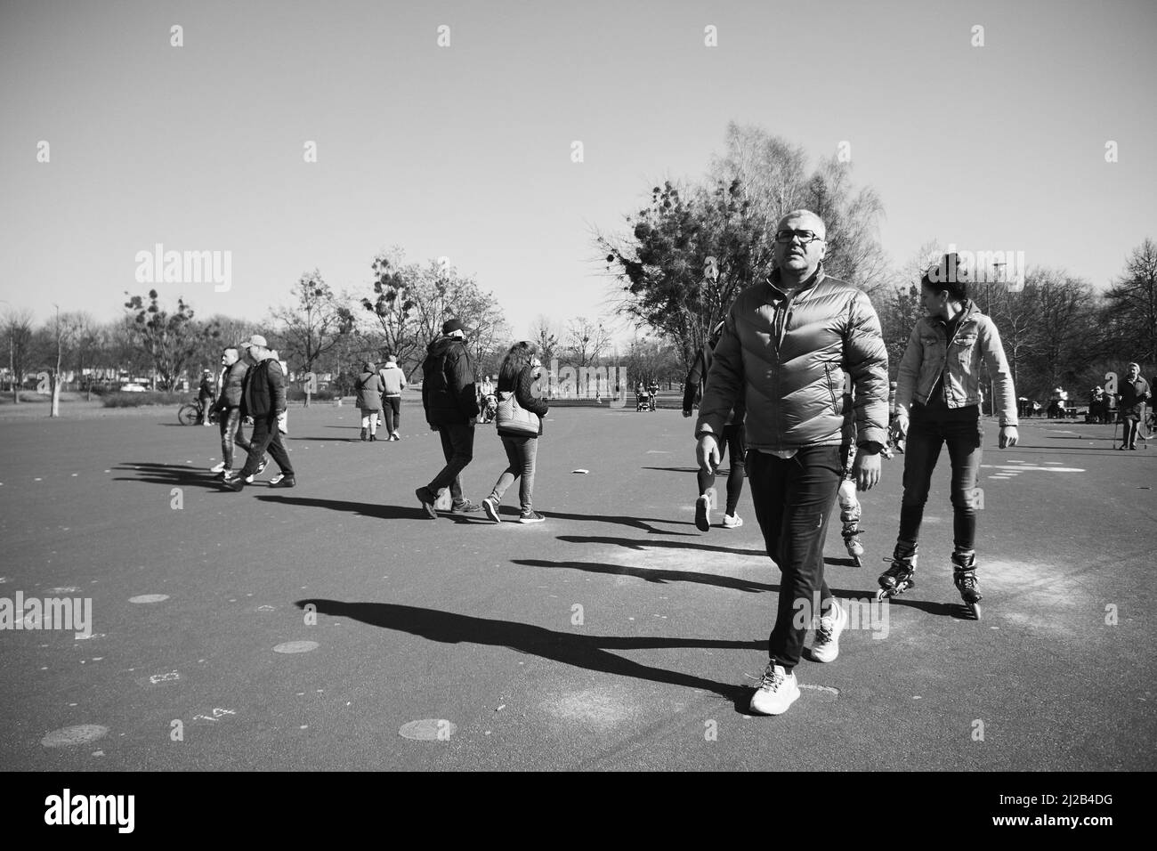 Una foto en escala de grises de personas caminando por la zona de asfalto en el parque Jan Pawla Foto de stock