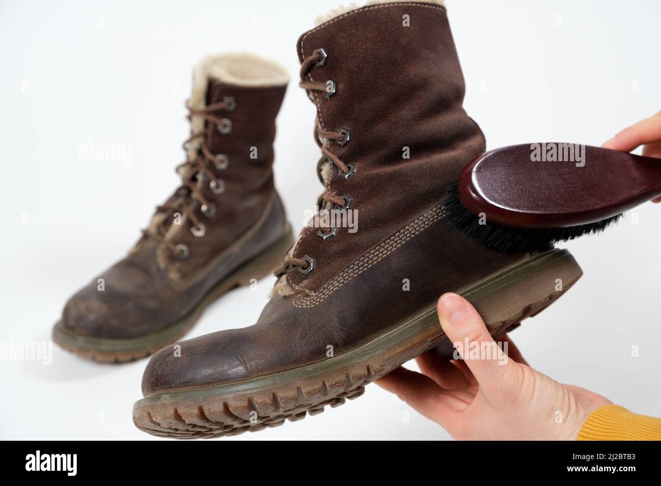 Una mujer aplica el spray a las botas de invierno nubuck marrón para mujer.  Cuidado repelente al agua de los zapatos, renovación y conservación del  color Fotografía de stock - Alamy