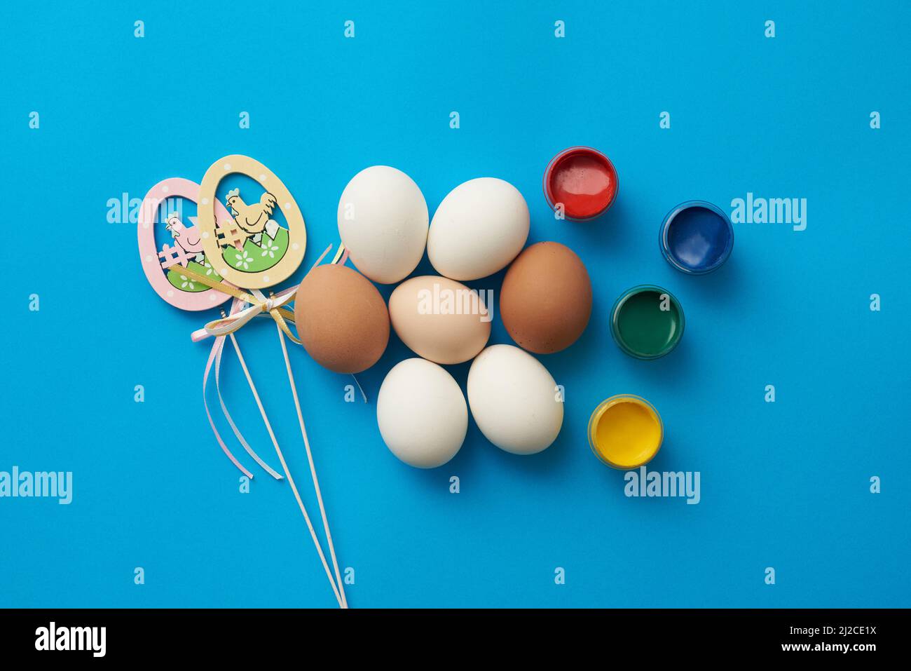 Plantilla temática de Pascua con huevos de pollo y pinturas sobre fondo azul Foto de stock