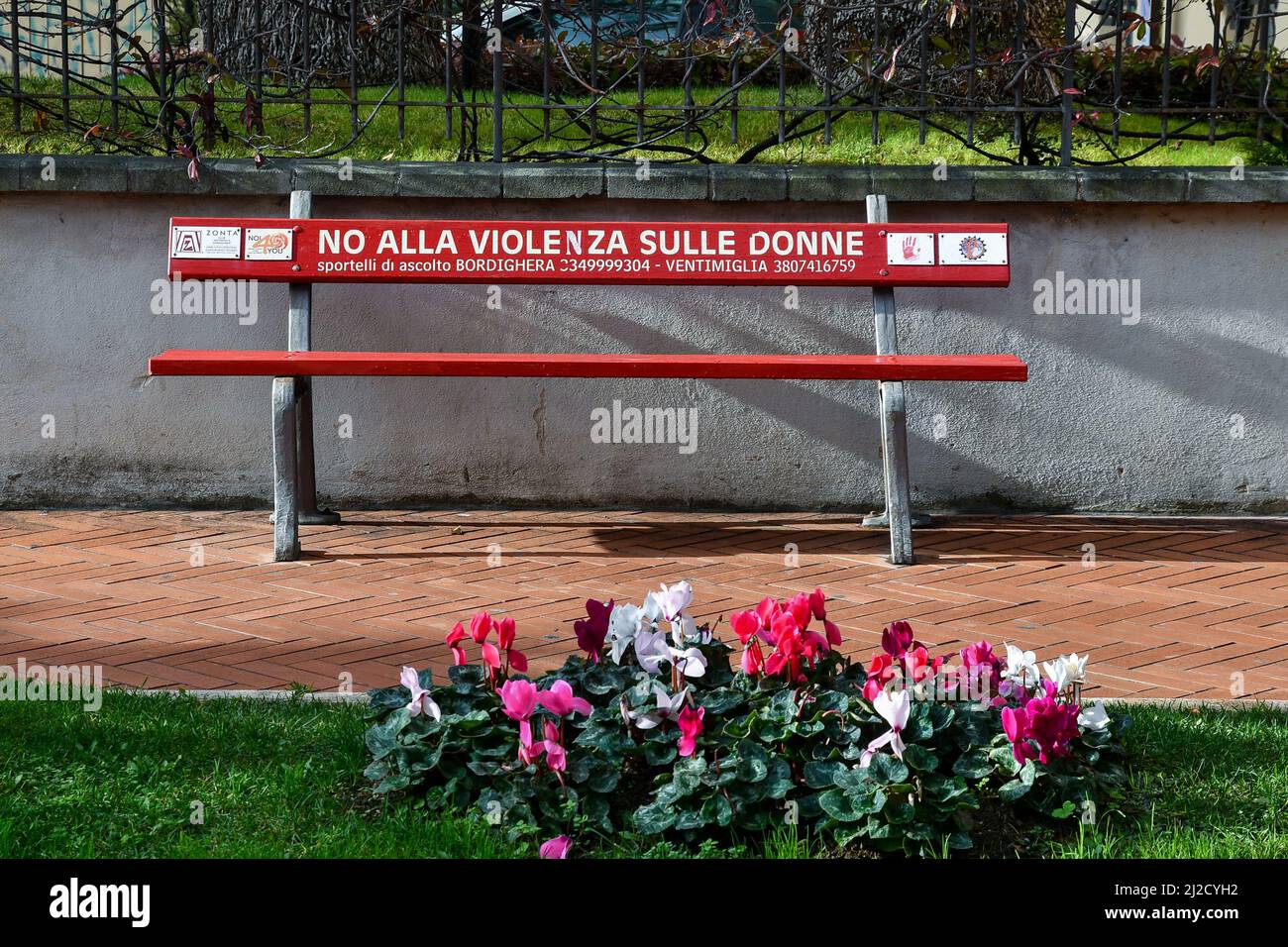 Un banco rojo con la inscripción: 'No a la violencia contra las mujeres' en una calle de Bordighera, Imperia, Liguria, Italia Foto de stock