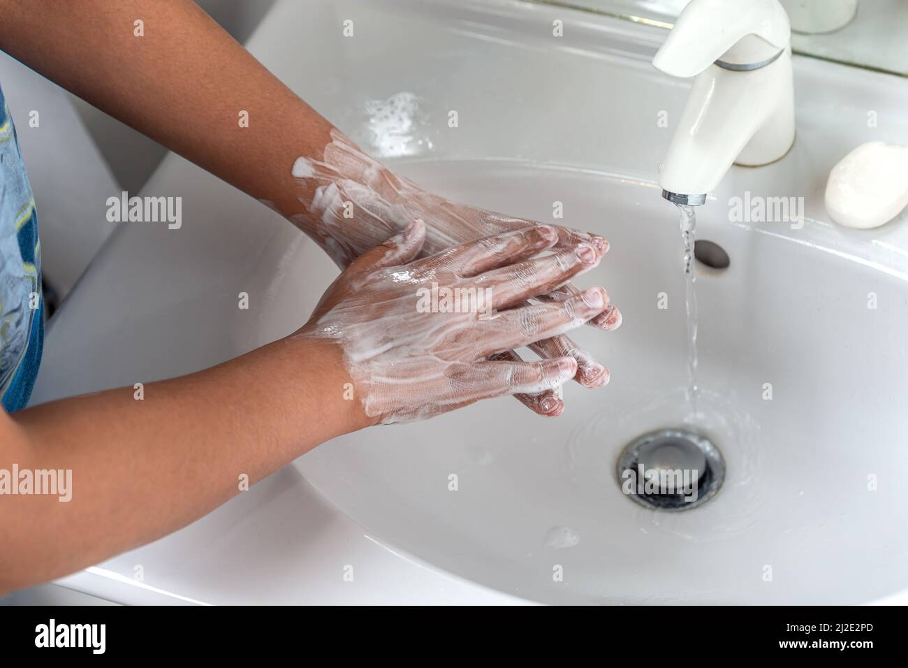Mujer lavando la mano con espuma de jabón y agua del grifo en el baño. Limpiar a mano bajo el grifo del fregadero para la higiene personal para prevenir la gripe y el coronavirus. Buen procedimiento de lavado de manos para matar bacterias, virus Foto de stock