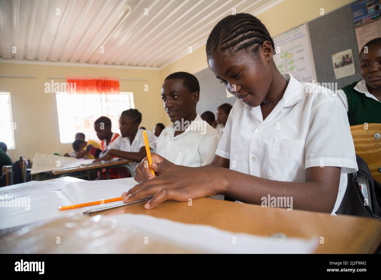 Estudiantes de secundaria que aprenden en pupitres en clase en la región de Oshana, Namibia, África meridional. Foto de stock