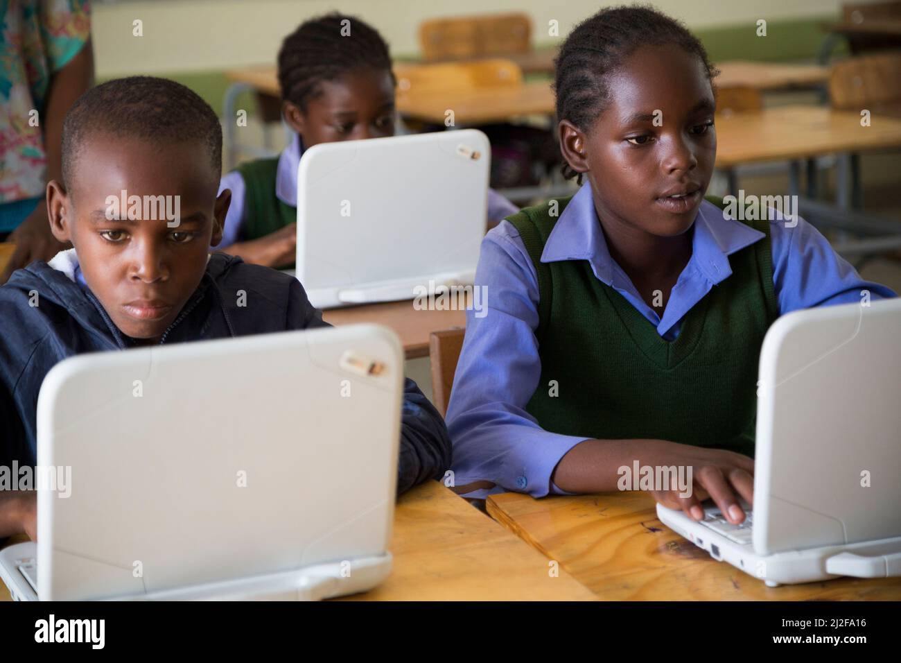 Los estudiantes Moses Wileinge (13, l), Evelyn Kaimbi (12, c) e Irena Nghidengwa (13, r) aprenden con nuevas computadoras portátiles en la Escuela Combinada Shikudule en Oshana Reg Foto de stock