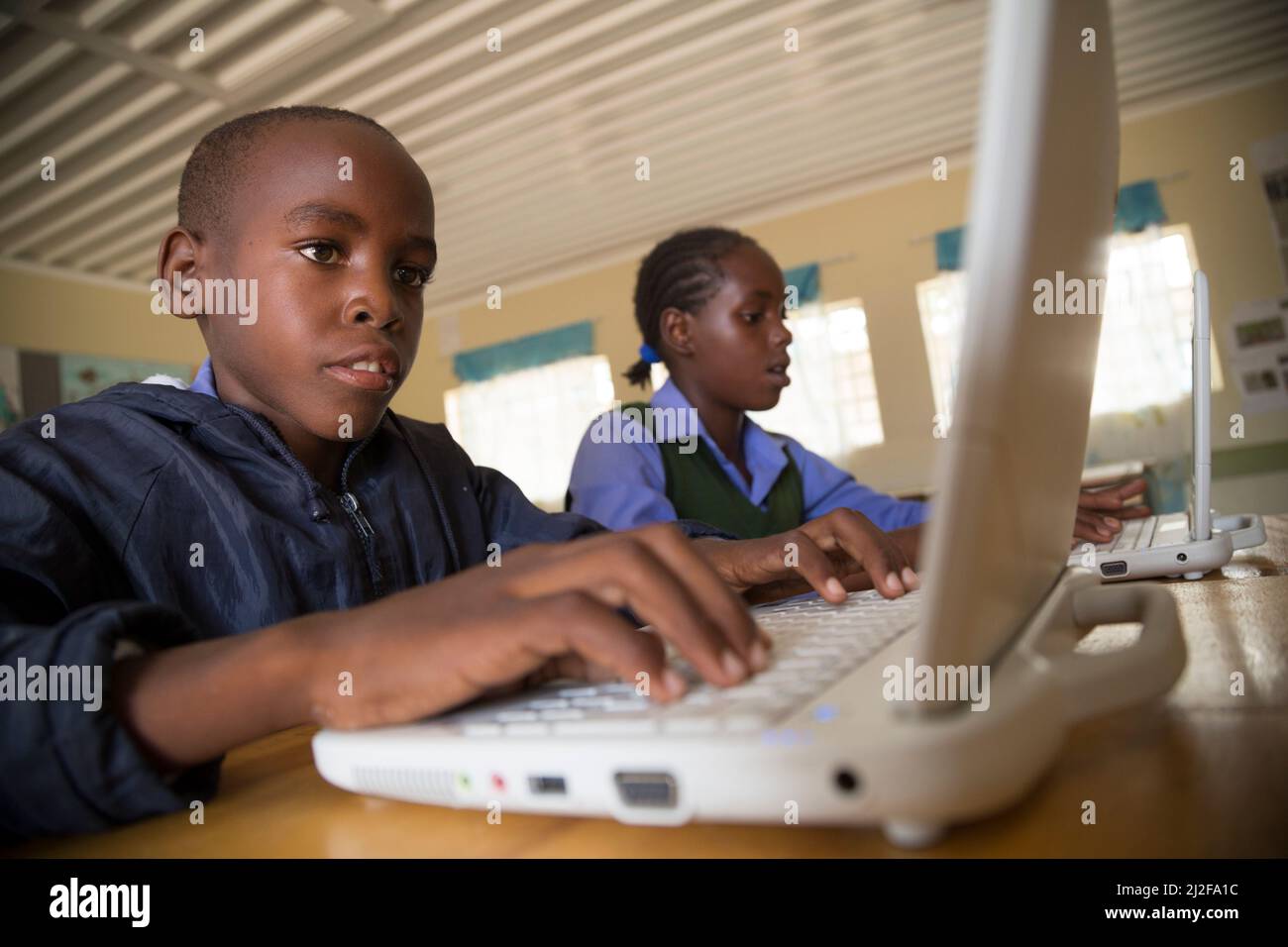 Los estudiantes Moses Wileinge (13) e Irena Nghidengwa (13) aprenden con nuevas computadoras portátiles en la escuela combinada Shikudule en la región de Oshana, Namibia. Como parte o. Foto de stock