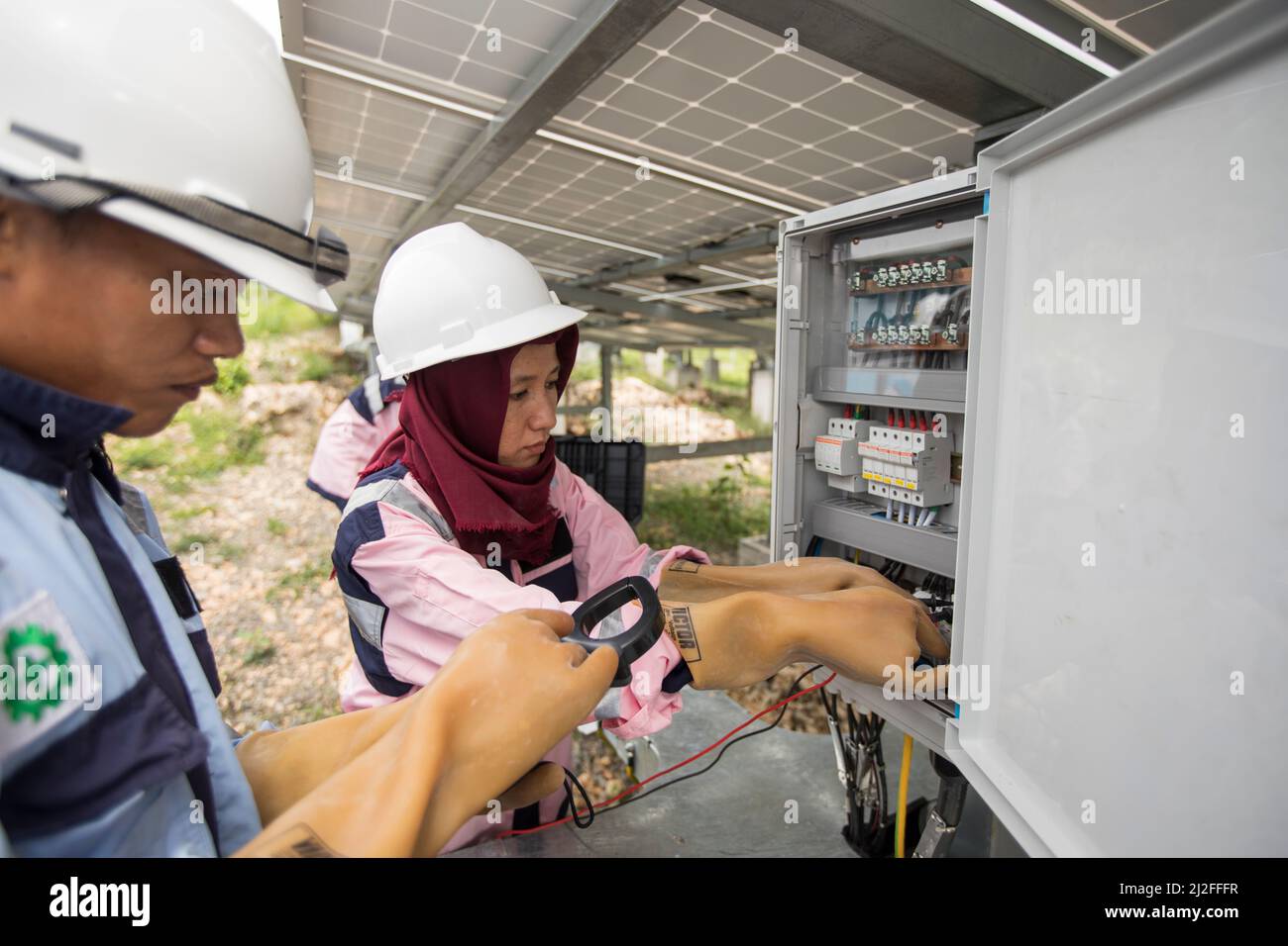 Técnicos eléctricos menores inspeccionan y mantienen paneles solares en la isla Karampuang, Indonesia, que fueron instalados como parte de la prosperidad verde Foto de stock