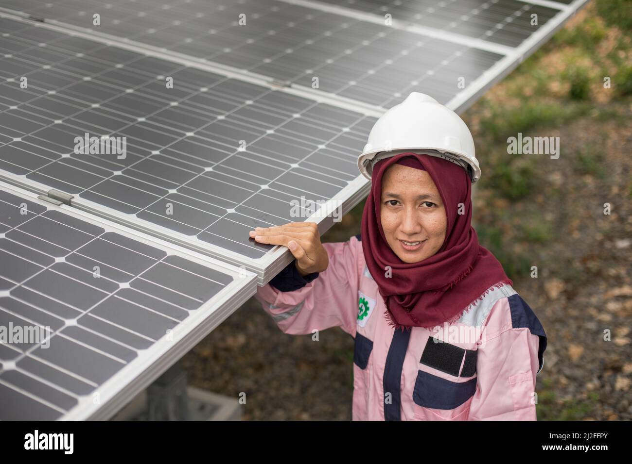 Un técnico eléctrico subalterno, Verawati (23 años), inspecciona y mantiene paneles solares en la isla de Karampuang, Indonesia, que se instalaron como parte del sistema Foto de stock
