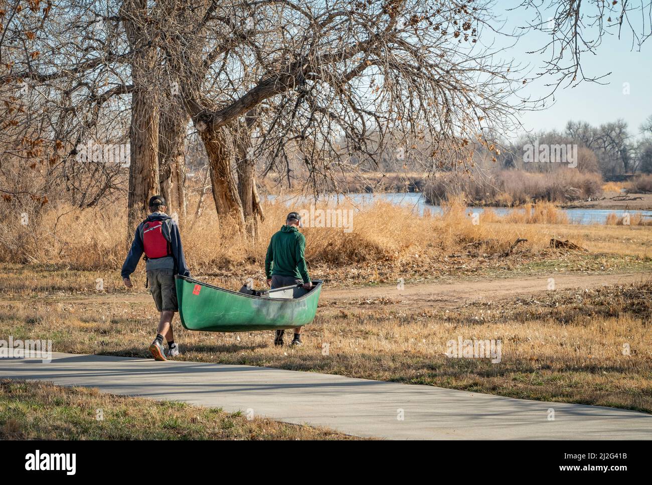 Evans, CO, EE.UU. - 26 de marzo de 2022: Los remeros masculinos llevan una canoa para lanzarse a principios de primavera en el río South Platte en Colorado. Foto de stock