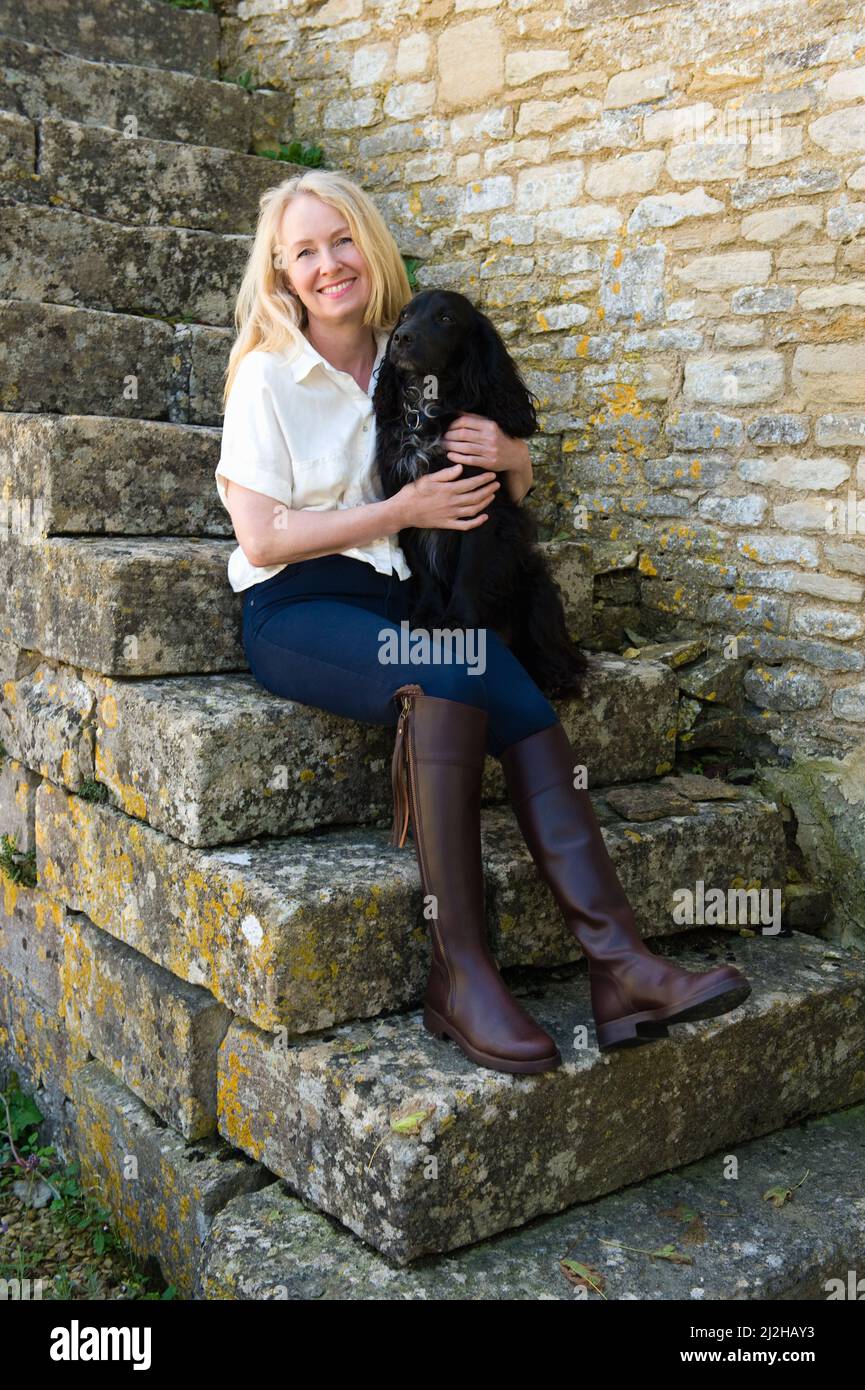 Retrato de una mujer sonriente sentada en escalones de piedra con un perro Foto de stock