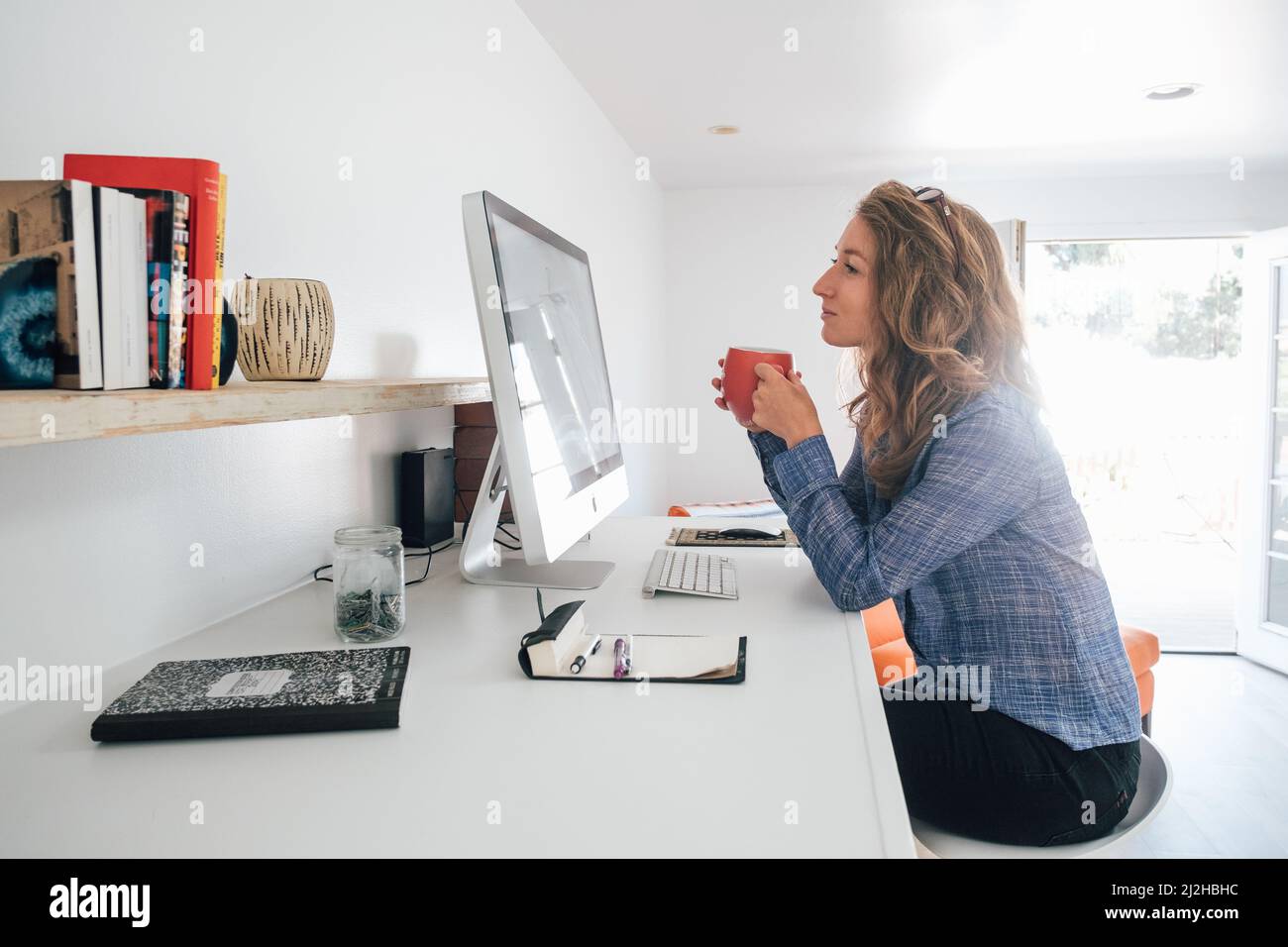 Mujer joven que trabaja desde casa en un pc de escritorio Foto de stock