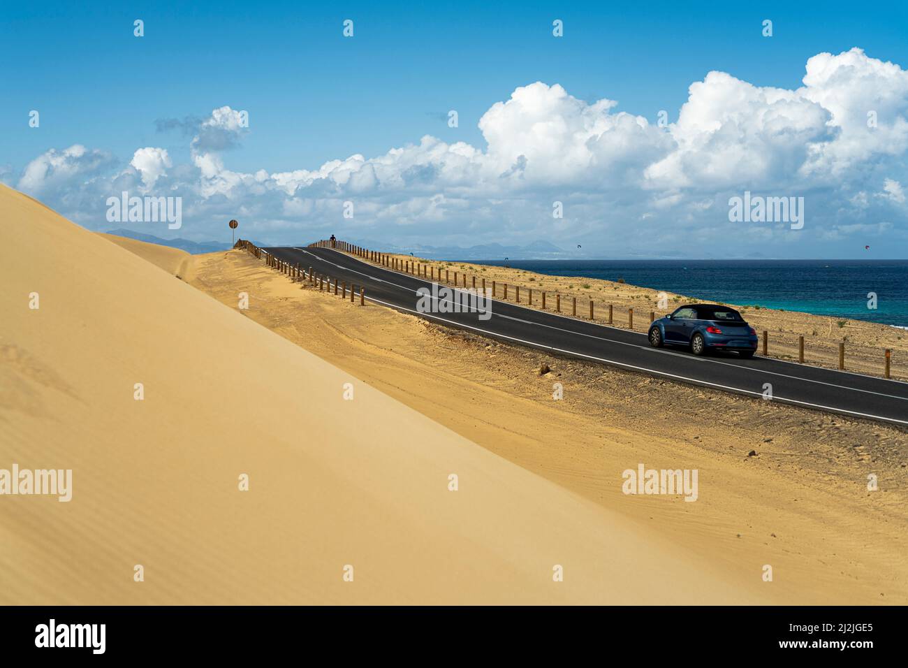 Coche viajando por carretera entre dunas de arena y el océano, Parque Natural de Corralejo, Fuerteventura, Islas Canarias, España Foto de stock