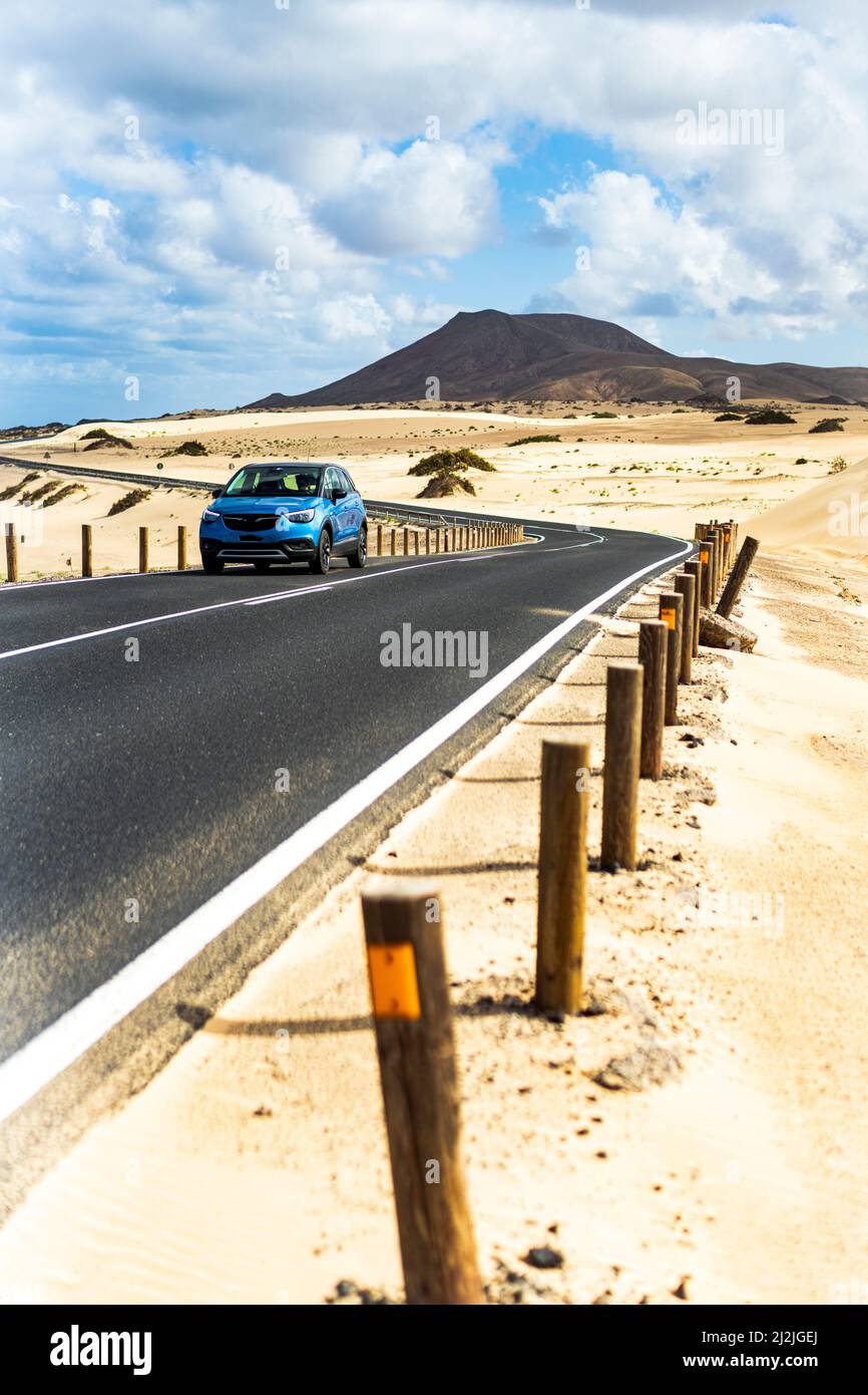 Coche viajando por carretera asfaltada en el desierto, Parque Natural de Corralejo, Fuerteventura, Islas Canarias, España Foto de stock
