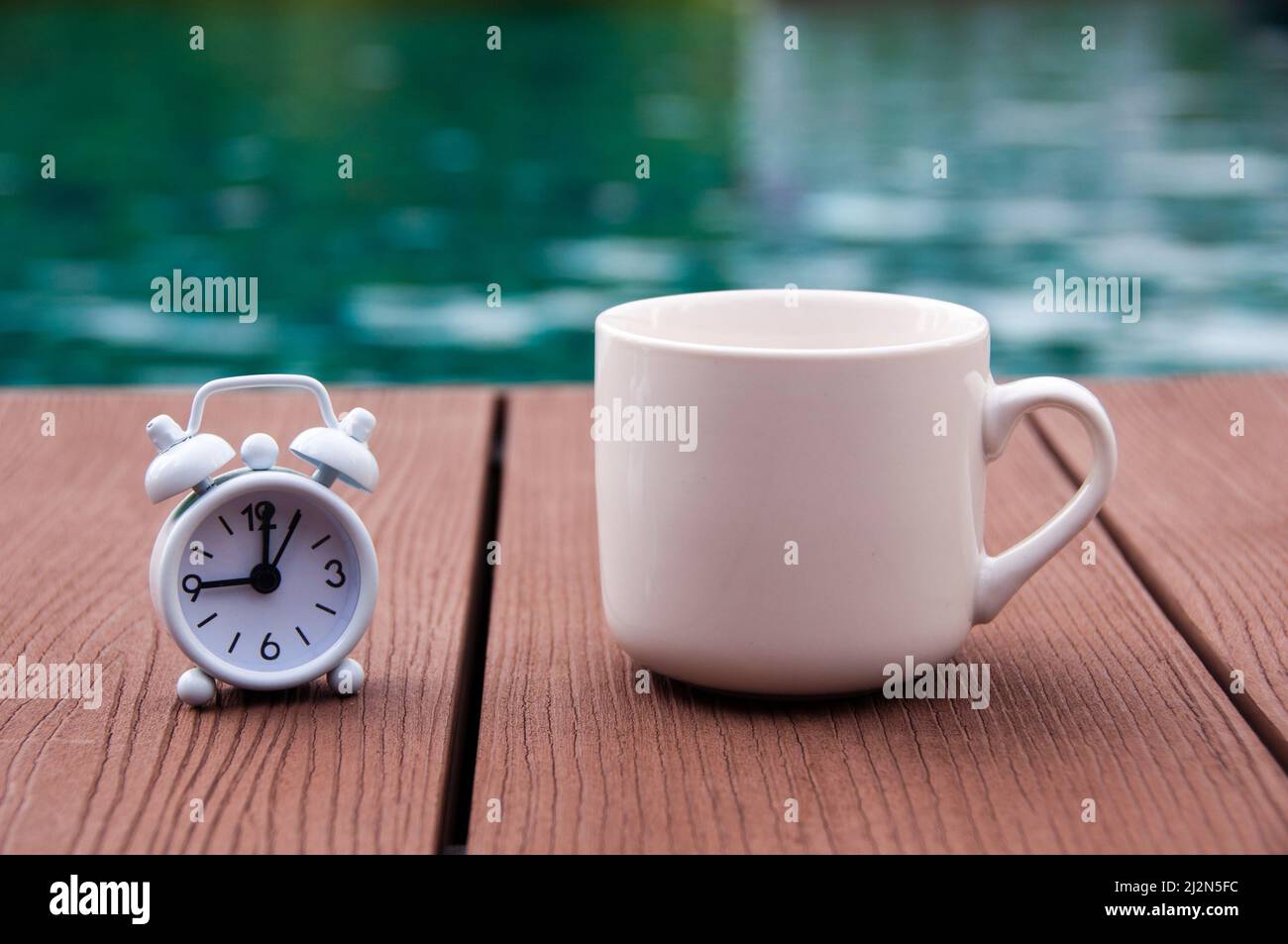 Reloj despertador blanco con suelo de madera y cafetera. Con fondo de  piscina borroso. Reloj ajustado a 9 o ' reloj Fotografía de stock - Alamy