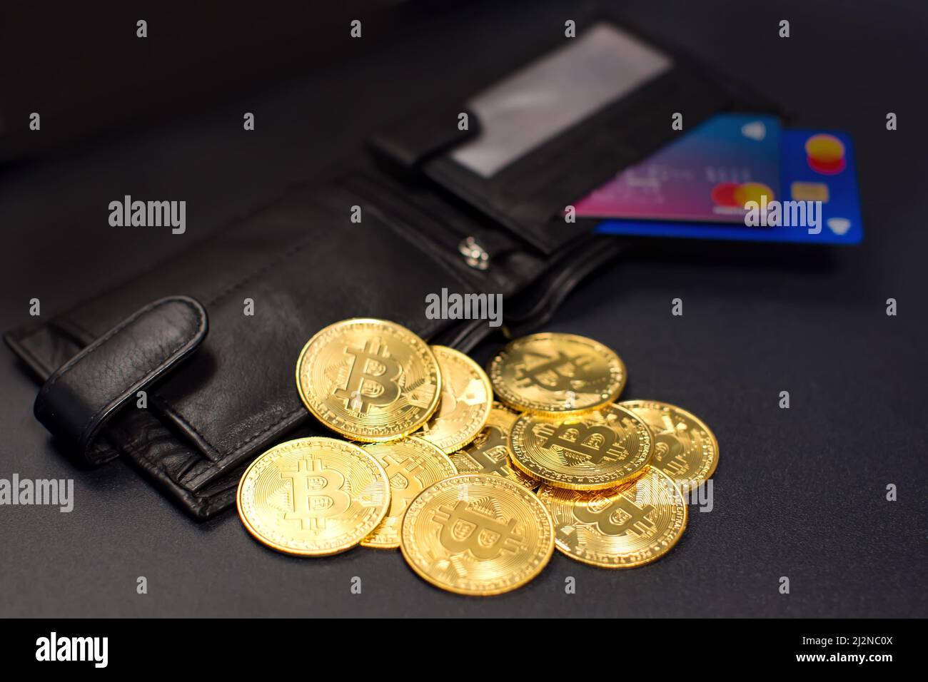 Monedas de Bitcoin y tarjetas de crédito en una cartera sobre el fondo de la pizarra Foto de stock