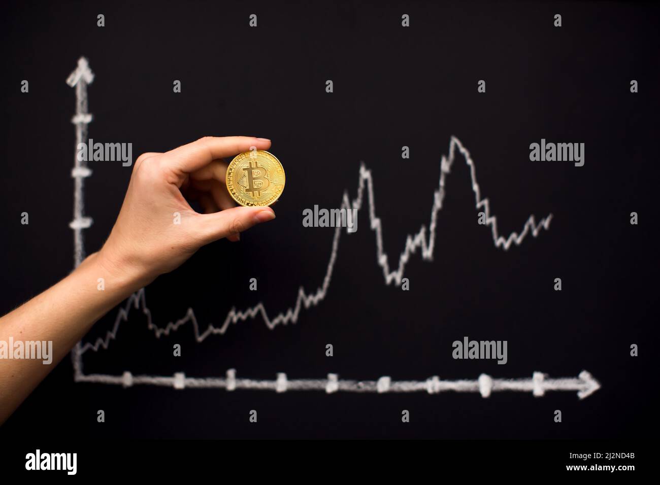 Gráfico de bitcoin con flecha hacia arriba en pizarra como criptomoneda en línea valor de comercio concepto creciente. Mano que sostiene bitcoin Foto de stock