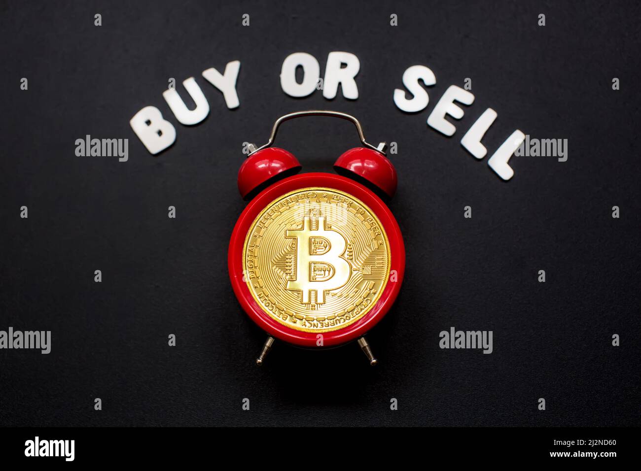 Bitcoin y despertador con el signo de 'Comprar o vender'. Concepto de plazo para invertir en criptomoneda de bitcoin. Foto de stock