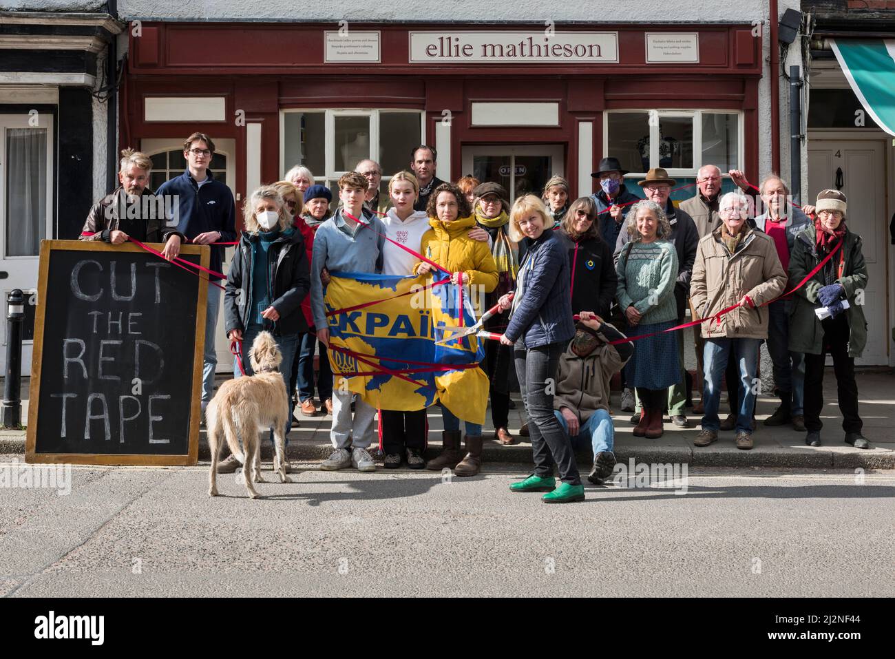 Protesta en nombre de refugiados ucranianos en la pequeña ciudad galesa de Presteigne, Powys, Reino Unido, el 2/4/22. Los marineros ucranianos Ellie Mathieson (blandiendo las cizallas rojas) y el patrocinador Louisa Collings (en amarillo), ambos de Presteigne, están presionando a la Oficina del Interior para que reduzca la burocracia en las solicitudes de visado de refugiados. La familia Louisa ha patrocinado con la ayuda de Ellie han estado esperando en Varsovia durante dos semanas, tiempo durante el cual el niño de 12 años se ha enfermado y ha terminado en el hospital por goteo. «Este limbo que les estamos infligiendo no hace más que aumentar su trauma», dice Louisa Foto de stock