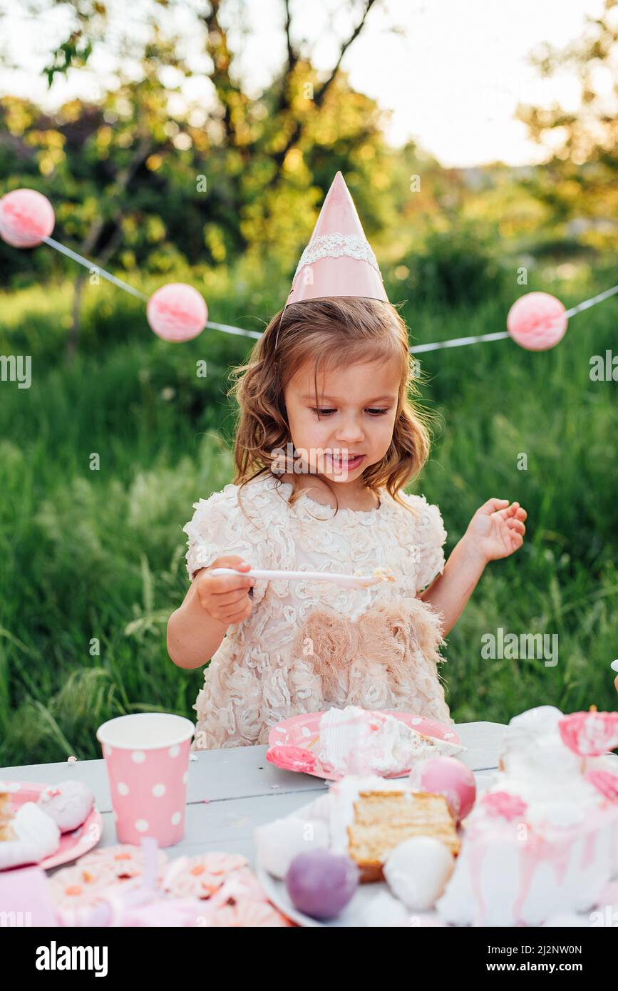 Feliz cumpleaños niña haciendo deseo soplando velas en pastel con  decoración rosa en hermoso jardín. 4 años de cumpleaños. el niño come feliz  cumpleaños rosa cu Fotografía de stock - Alamy