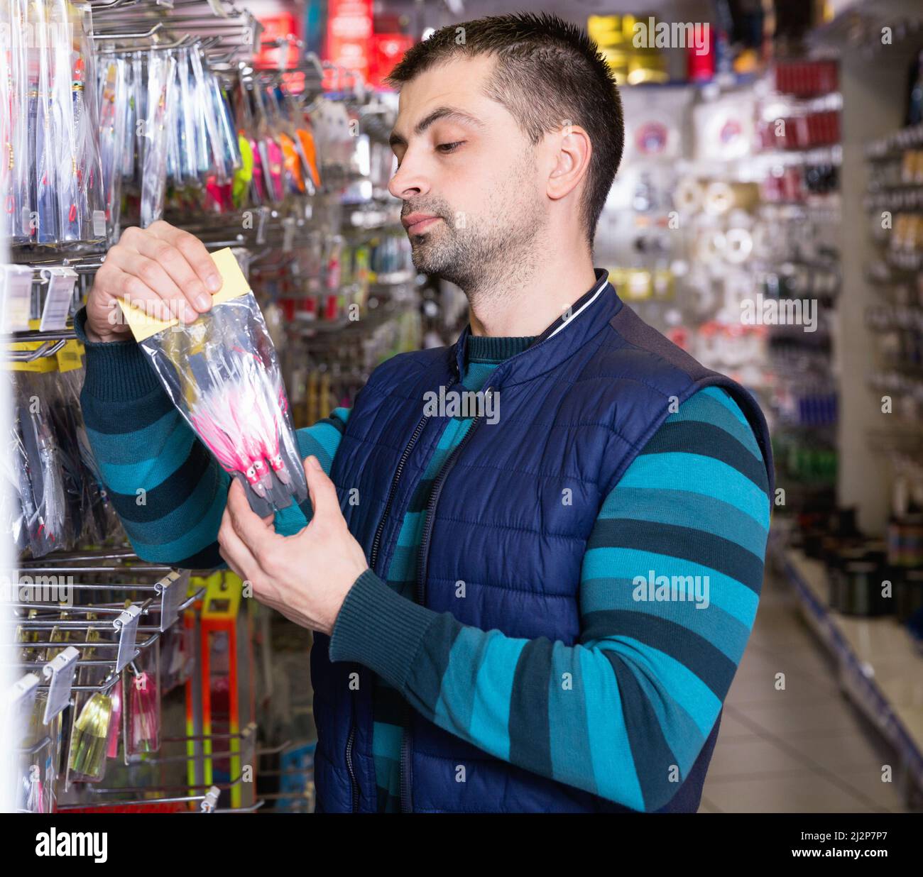 Hombre cliente elige cebos de pesca cerca de pie en la tienda de deportes  Fotografía de stock - Alamy