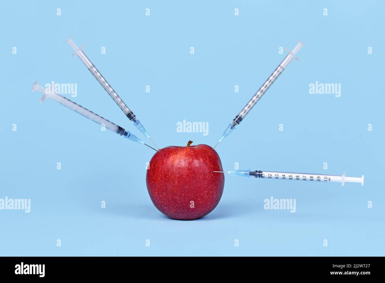 Se inyecta fruta de manzana con jeringas. Concepto para organismos genéticamente modificados Foto de stock