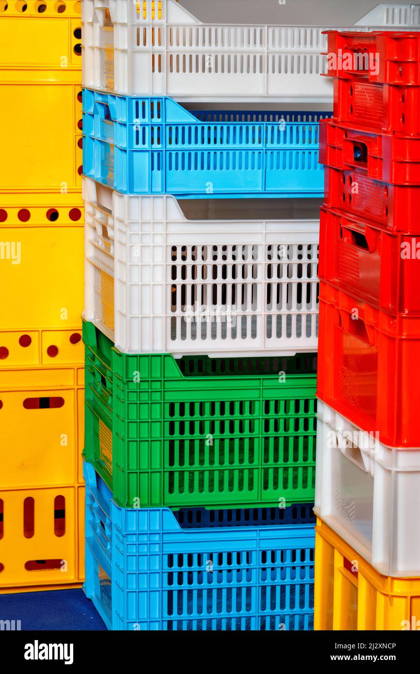Cajas de carga de plástico de varios colores apiladas unas encima de otras.  Imagen vertical Fotografía de stock - Alamy