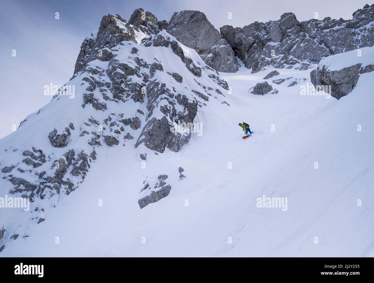 Snowboarder con una tabla de salpicar en el descenso de la barranca de roca Eppzirler Scharte en una excursión de esquí en el Karwendel Foto de stock