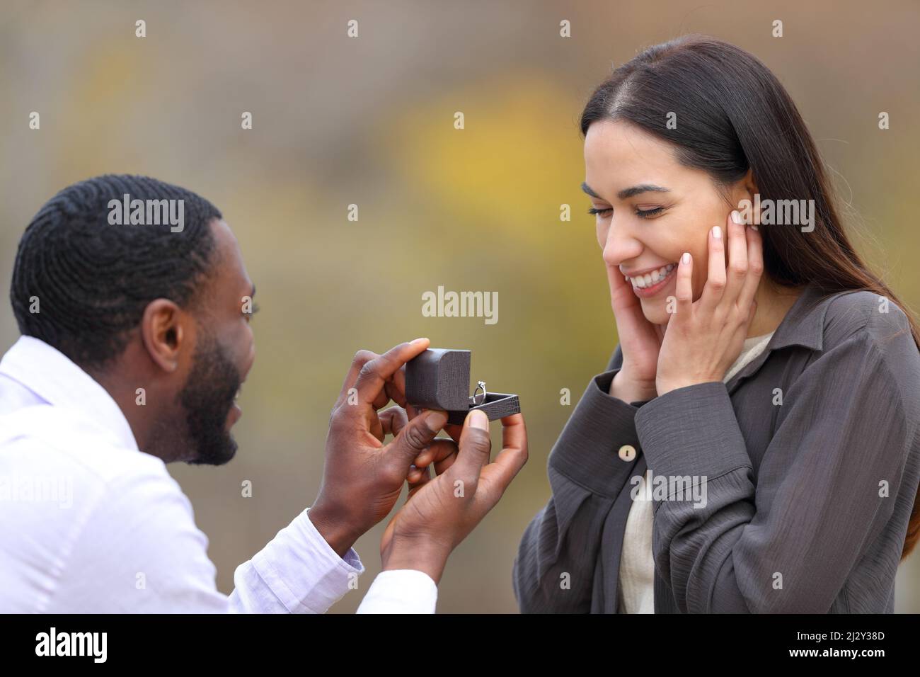 Pareja interracial que propone matrimonio en un parque Foto de stock