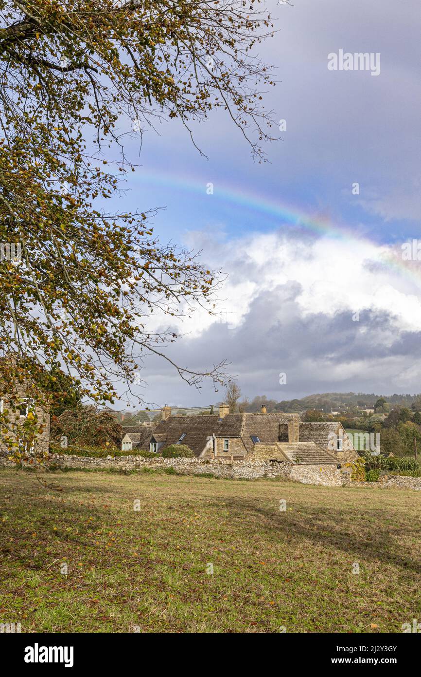 Un arco iris otoñal en el pueblo Cotswold de Sevenhampton (mirando hacia Brockhampton), Gloucestershire, Inglaterra Reino Unido Foto de stock