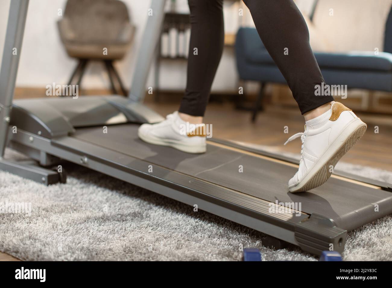 Primeros planos de los pies atléticos corriendo en la cinta de andar en  casa. Vista lateral de los zapatos blancos para mujer haciendo ejercicio en  la cinta de correr. Zapatillas de entrenamiento
