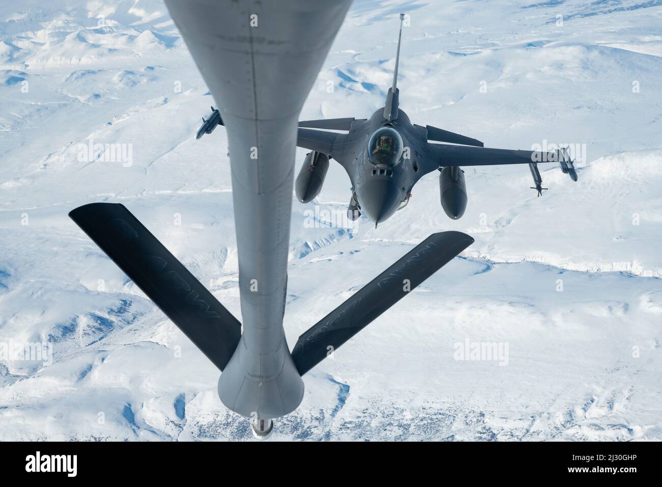 16 de marzo de 2022 - Base Conjunta Elmendorf-Richardson, Alaska, EE.UU. - Un halcón de combate de la Fuerza Aérea de EE.UU. F-16, asignado al ala de combate 180th Fighter, vuela a su posición para ser reabastecido por un avión Stratotanker KC-135, asignado al escuadrón de repostaje de aire de 97th, durante el ejercicio 2022 DEL COMANDO Norte de EE.UU., 15 de marzo de 2022. AE22 es un ejercicio bienal de defensa para el Comando Norte de los Estados Unidos y las Fuerzas Armadas Canadienses para demostrar y ejercer una capacidad conjunta para desplegar y operar rápidamente en el Ártico. (Imagen de crédito: © U.S. Air Force/ZUMA Press Wire Service/ZUMAPRESS.com) Foto de stock