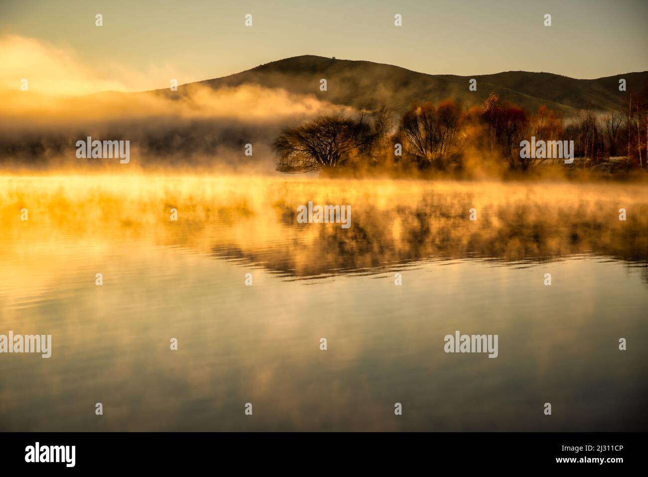 Malhumorado nube baja sobre la superficie del agua al amanecer sobre el brazo de Wairepo cerca de Twizel Foto de stock