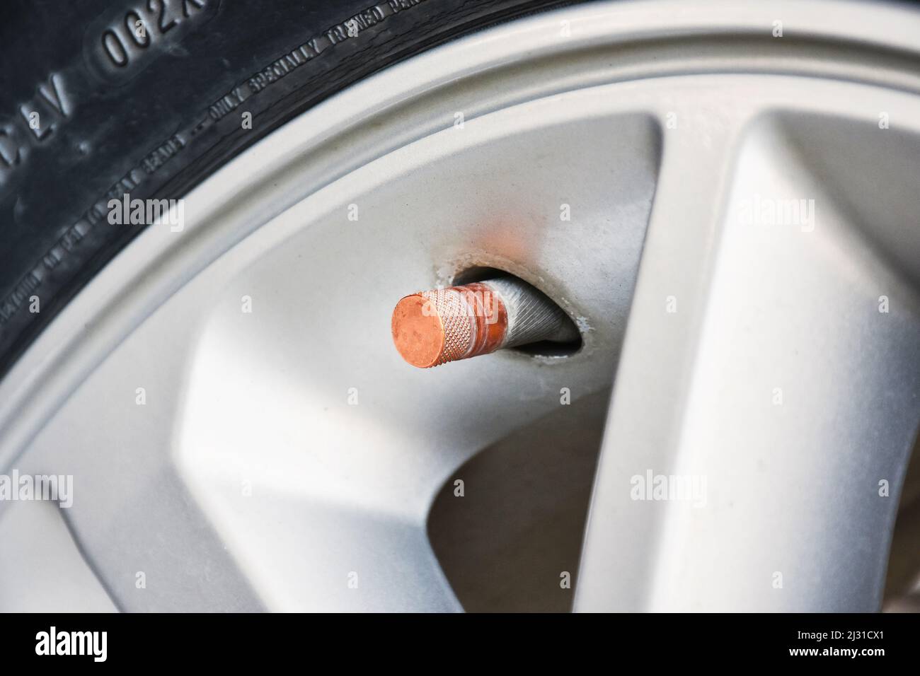 Vástago de la válvula del neumático con una tapa naranja de la llanta de gris del automóvil Fotografía stock - Alamy