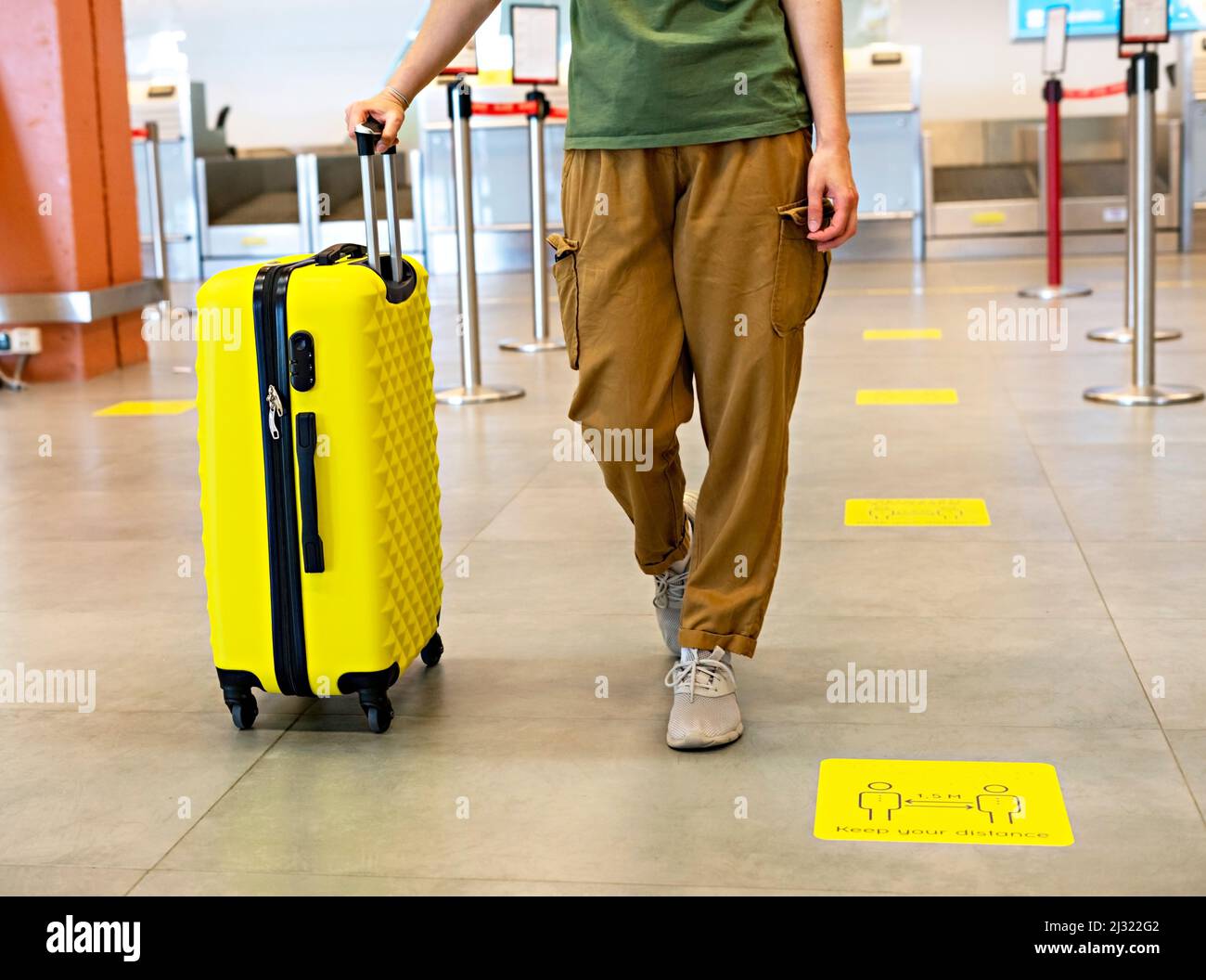 mujer informal con una maleta amarilla en el aeropuerto en el concepto de viaje sin rostro de la terminal Foto de stock