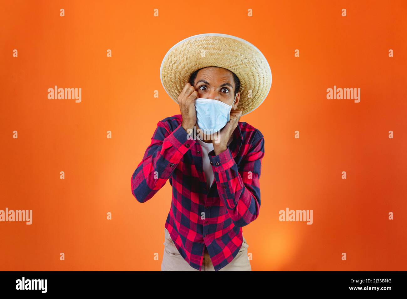 Hombre Negro con Junina Conjunto de fiesta sosteniendo una tableta o móvil  aislado sobre fondo naranja. Hombre joven con ropa tradicional para Festa  Junina Fotografía de stock - Alamy