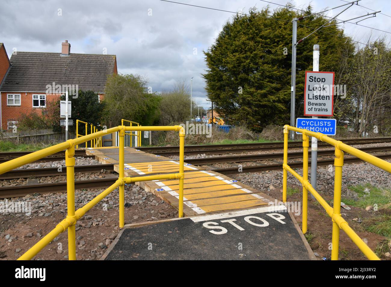 Típico British Railway Foot Crossing con barandillas de alta visibilidad y señales de advertencia de seguridad Foto de stock
