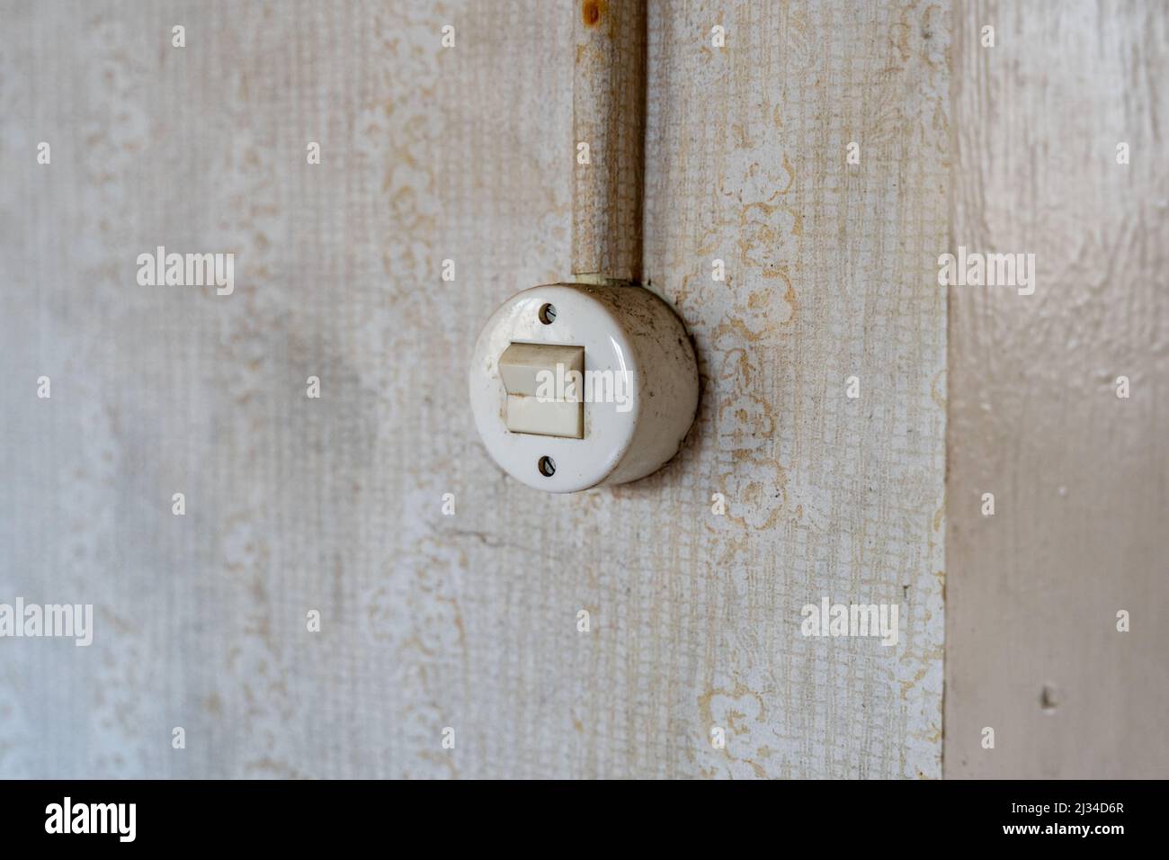 Interruptor de luz redonda antiguo en una pared con un cable. Interruptor  de palanca retro en un apartamento de Alemania del Este. Diseño interior  del pasado en malas condiciones de suciedad Fotografía